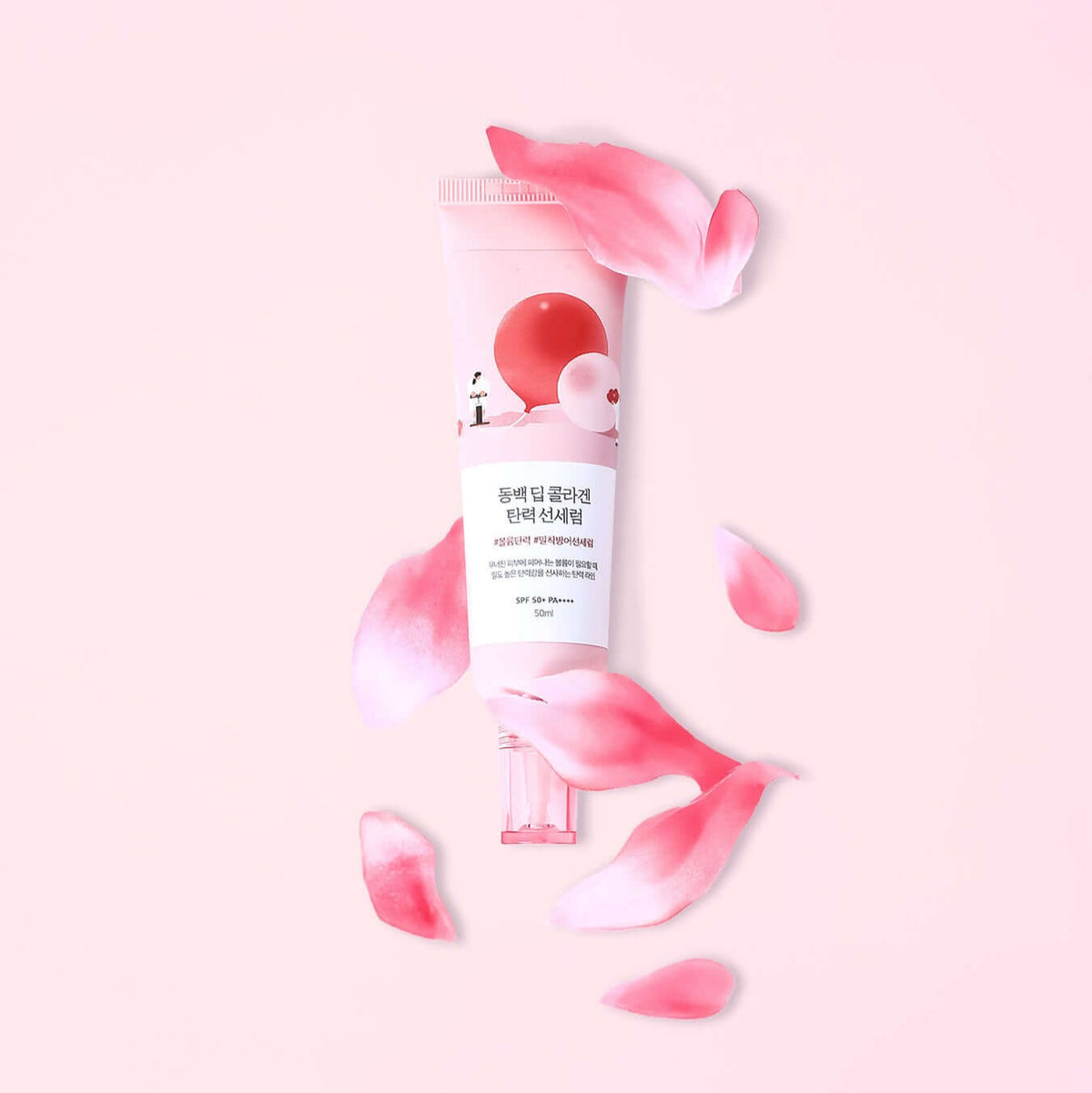 ROUND LAB Dongbaek Deep Collagen Elasticity Sun Serum 50ml surrounded by pink petals on a pastel background