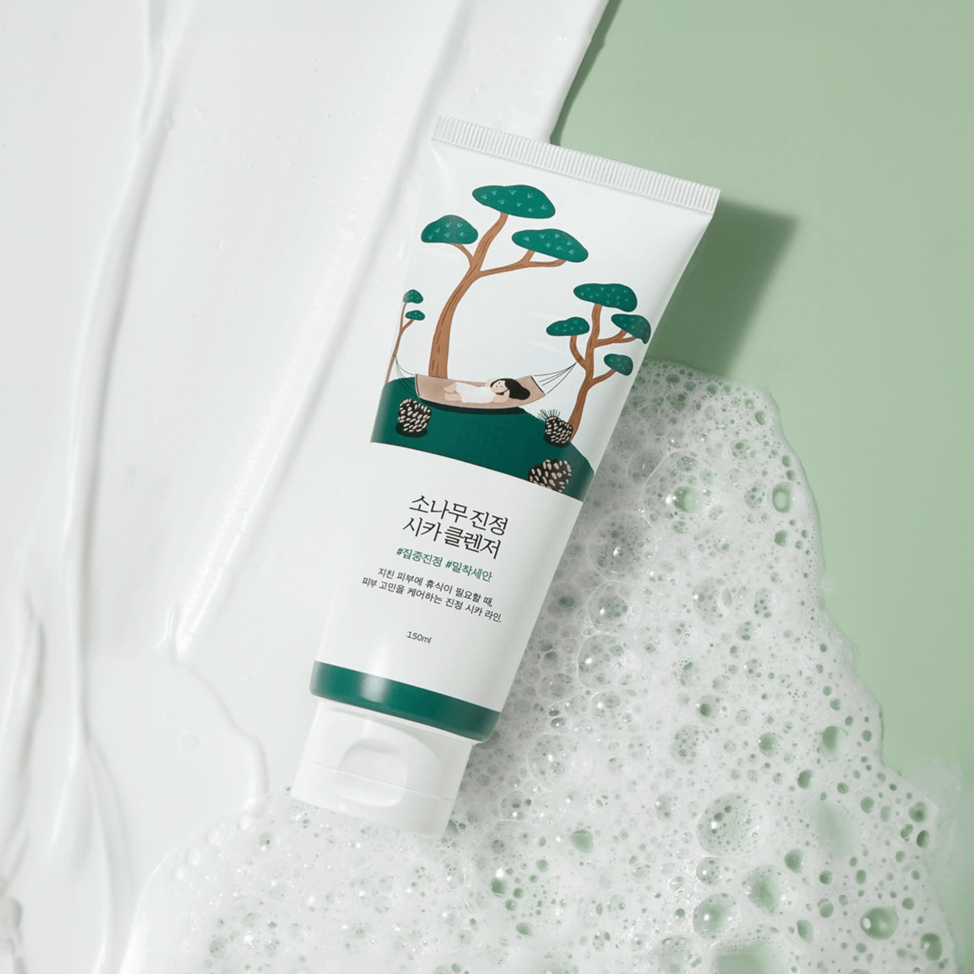 Image of ROUND LAB Pine Calming Cica Cleanser 150ml with soothing pine tree design on a green and white textured background.