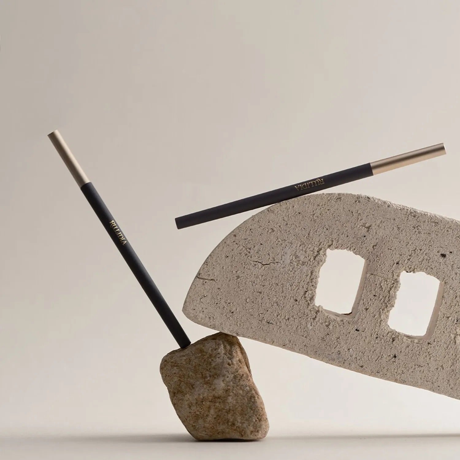RULIDIA Easy Detail Brow pencils placed artistically on stone and brick backdrop, showcasing sleek design and precision for ideal brow definition.