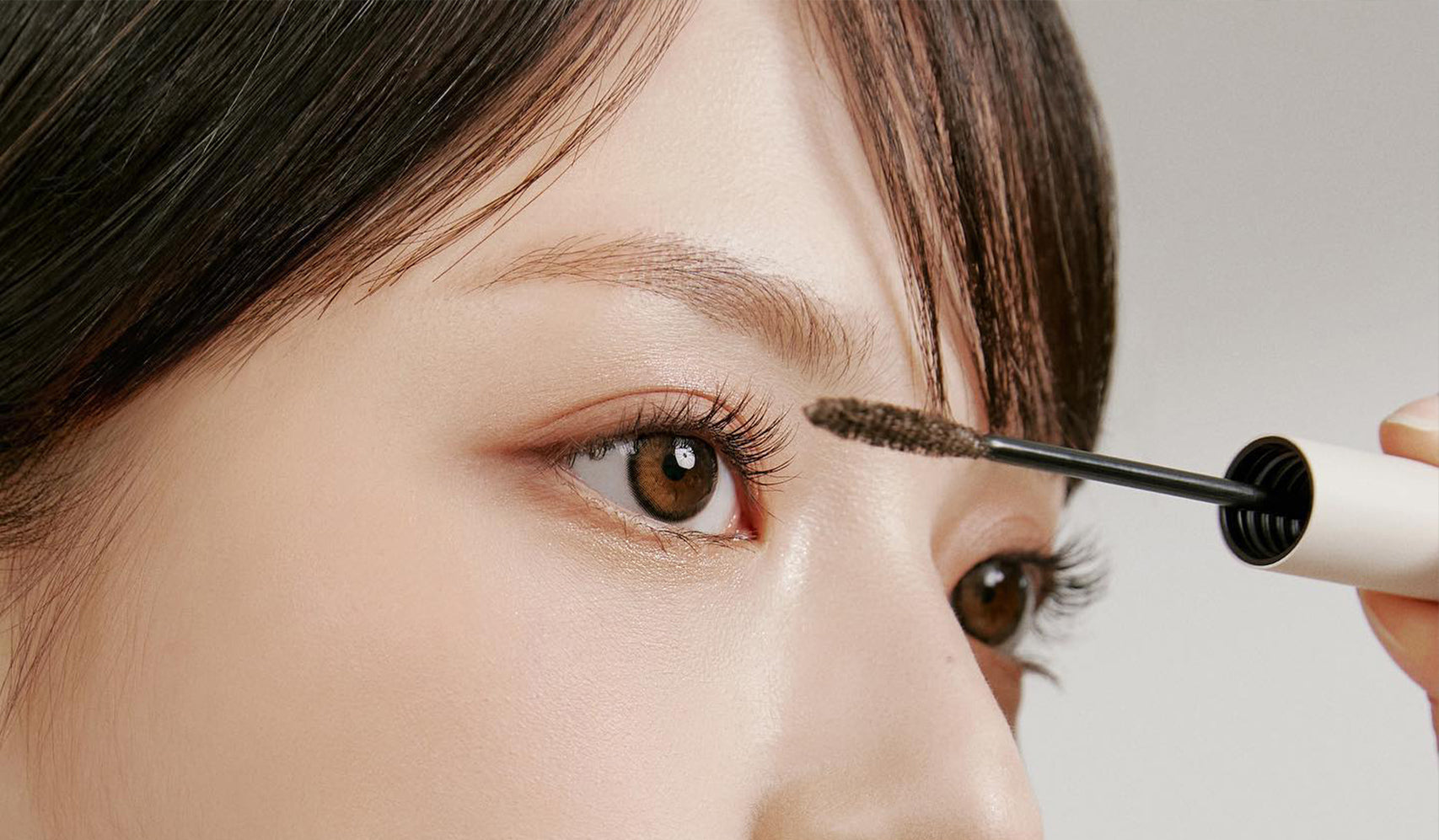 Close-up of a person applying mascara, focusing on eyelashes and eye makeup enhancement.
