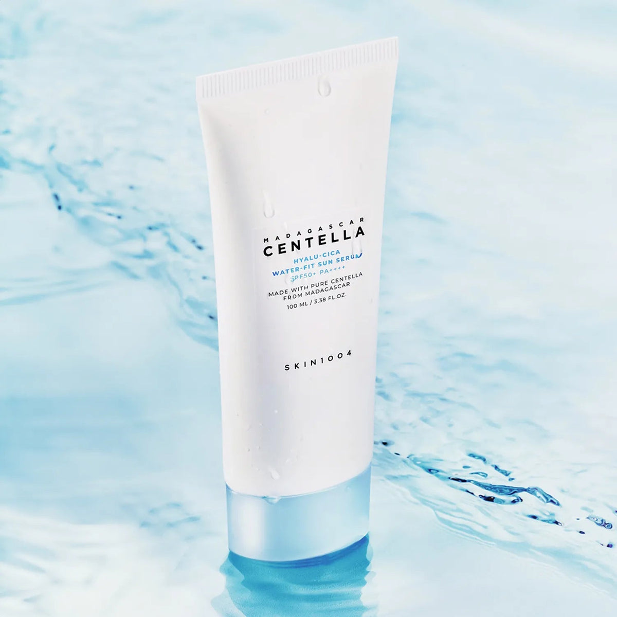 SKIN1004 Madagascar Centella Hyaluronic Acid Water-Fit Sun Serum 100ml tube placed on a serene water background