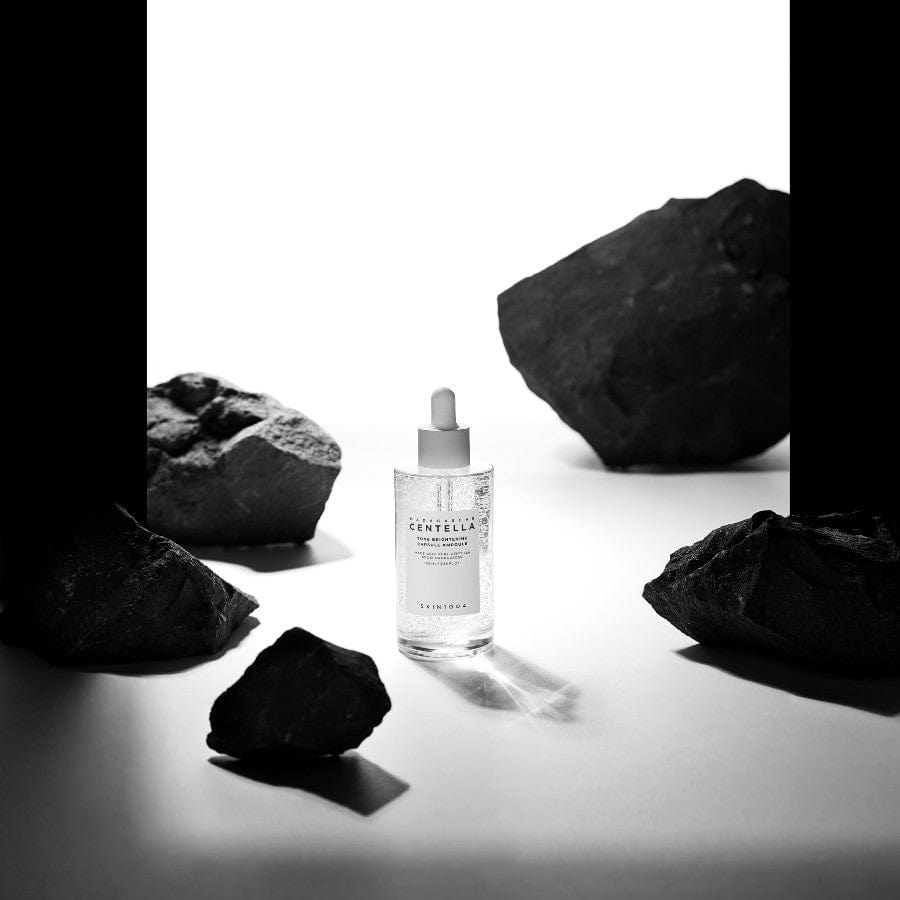 SKIN1004 Madagascar Centella Tone Brightening Capsule Ampoule 100ml bottle surrounded by rocks on a white background