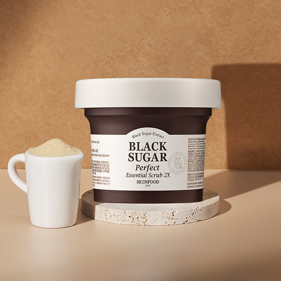 SKINFOOD Black Sugar Perfect Essential Scrub 2x 210g displayed next to a small white bowl of sugar on a beige background