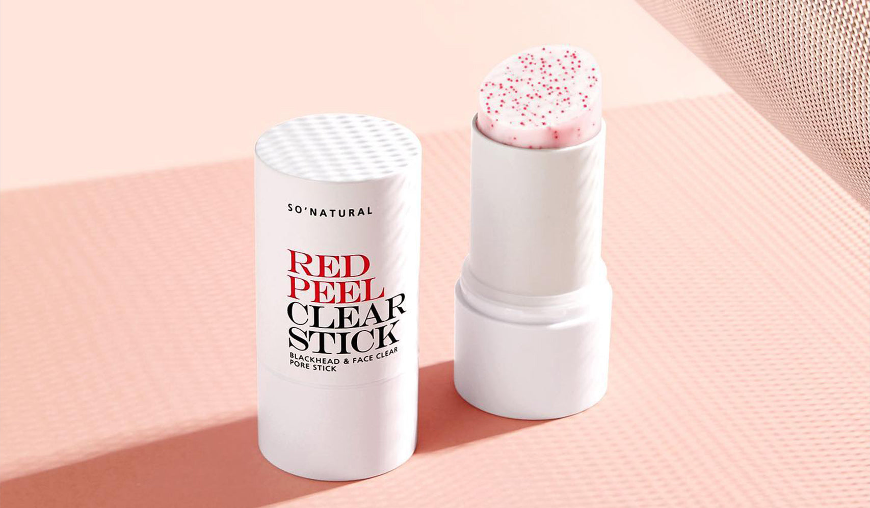 Red Peel Clear Stick for deep exfoliation and skin care on a pink textured surface.