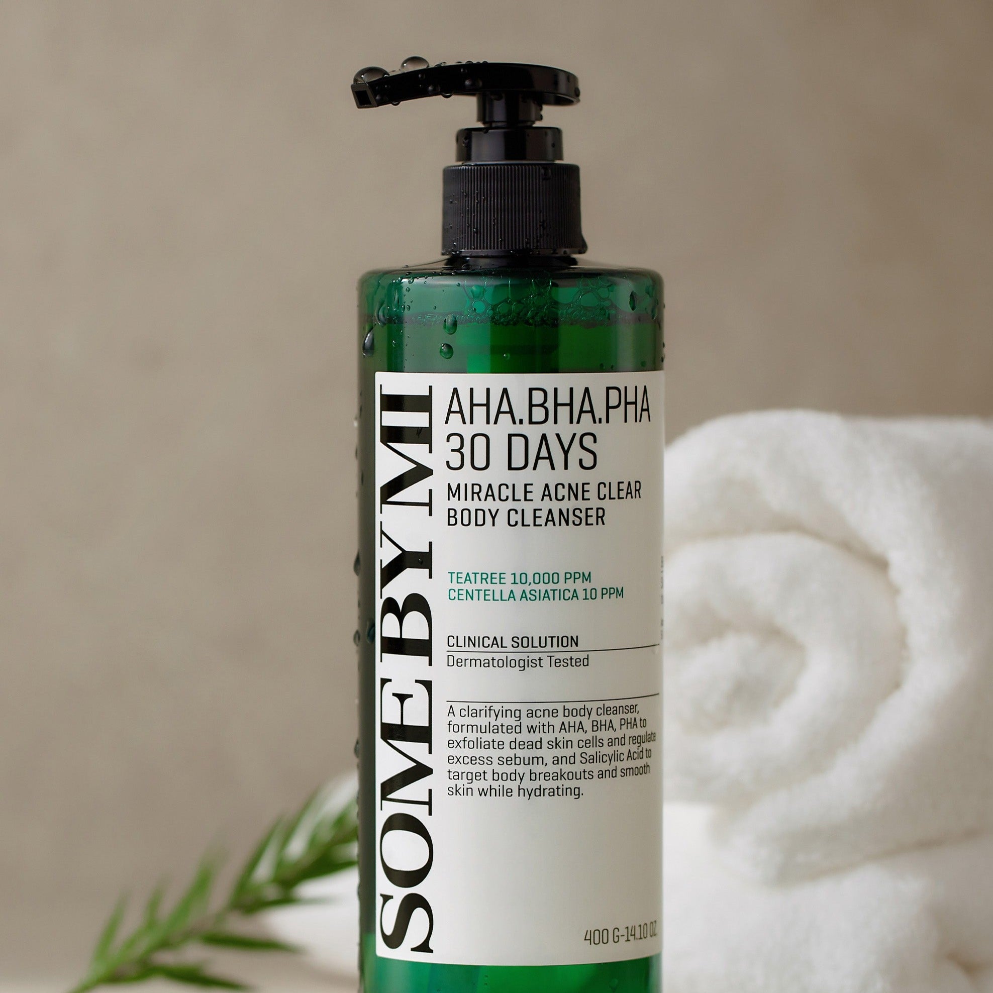 SOME BY MI AHA.BHA.PHA Miracle Acne Clear Body Cleanser 400g bottle next to white towels and greenery.