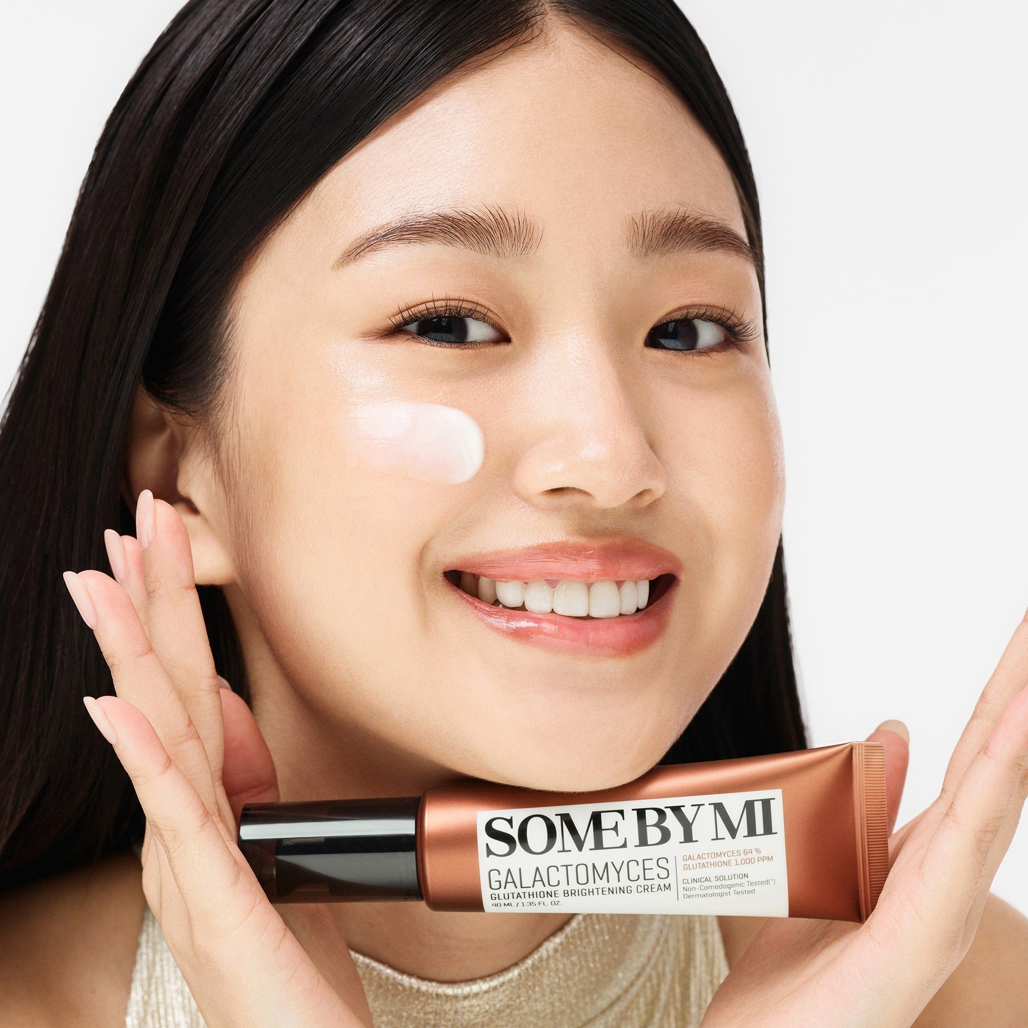 Smiling woman holding SOME BY MI Galactomyces Glutathione Brightening Cream 40ml, showcasing product application.