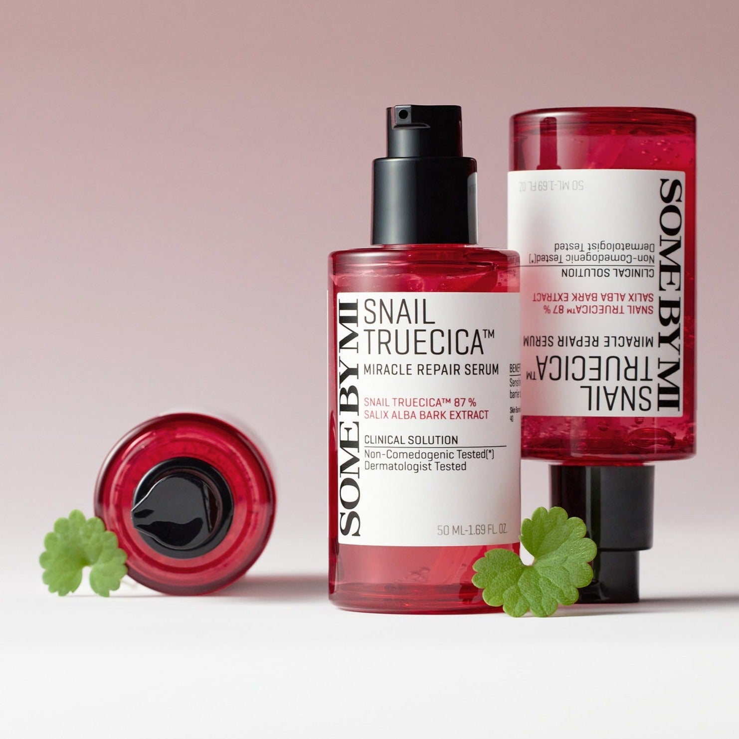 SOME BY MI Snail Truecica Miracle Repair Serum 50ml bottles with green leaves, showcasing skincare product packaging and design.