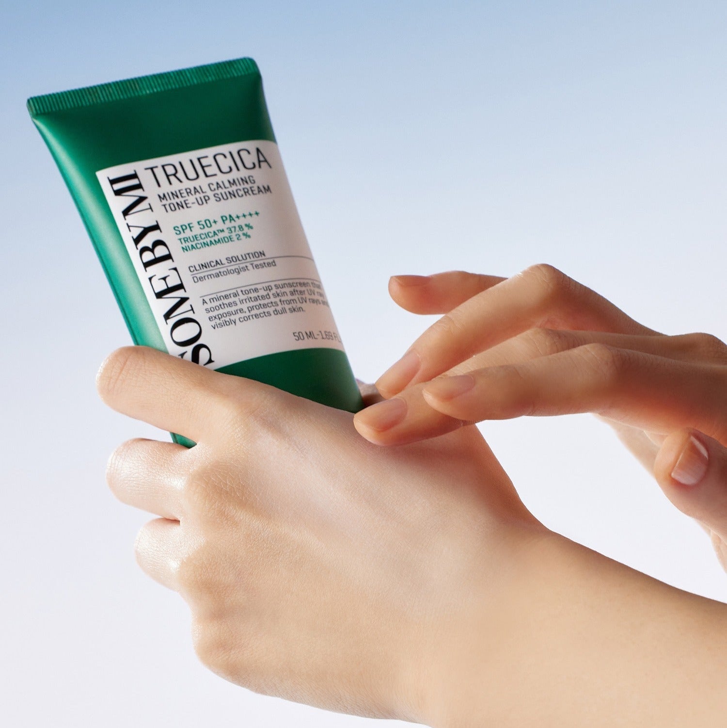 Hands holding SOME BY MI Truecica Weaponless Calming Tone Up Sun Cream 50ml