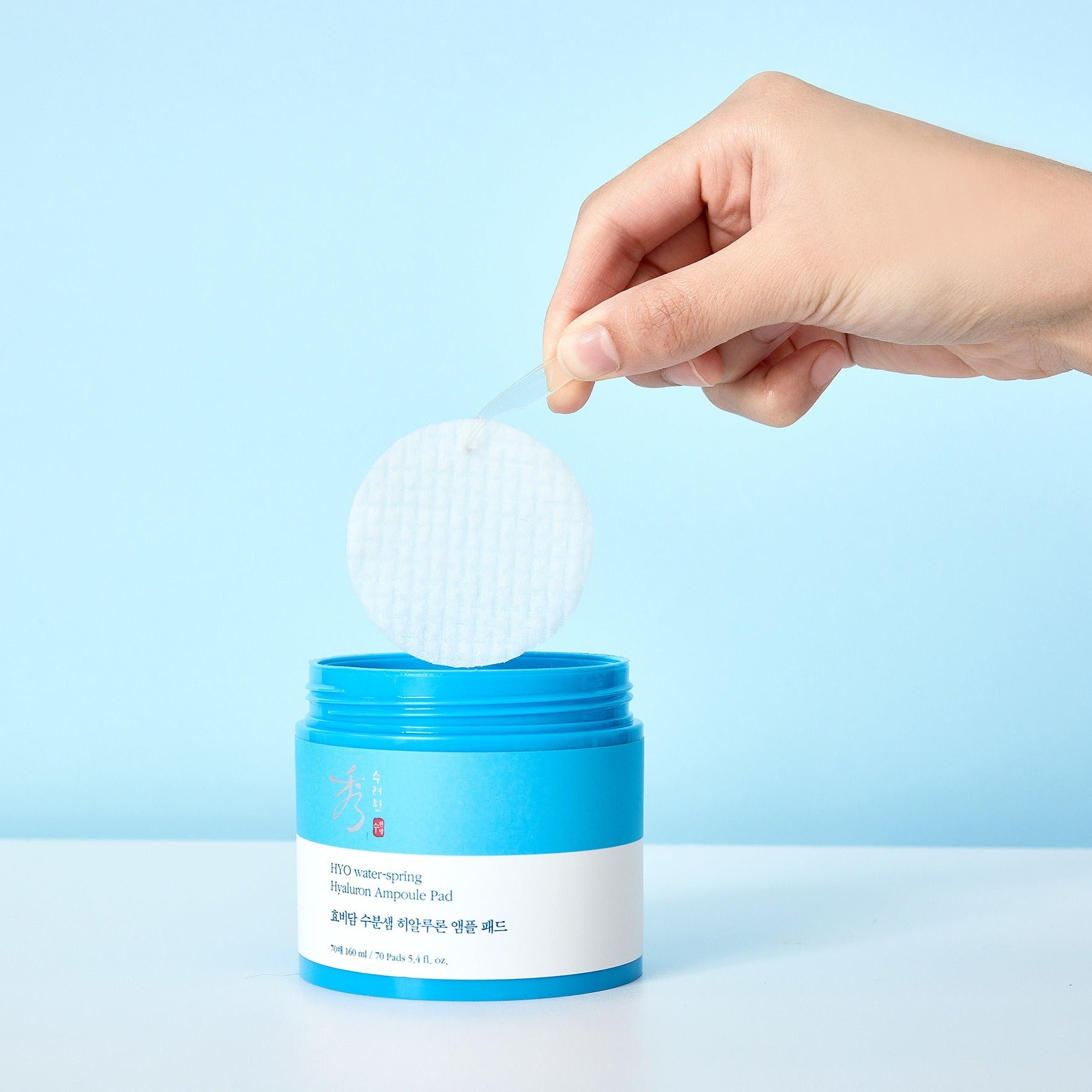 Hand holding a pad from SOORYEHAN Moiture Spring Hyaluronic Ampoule Pads 70 Sheets container