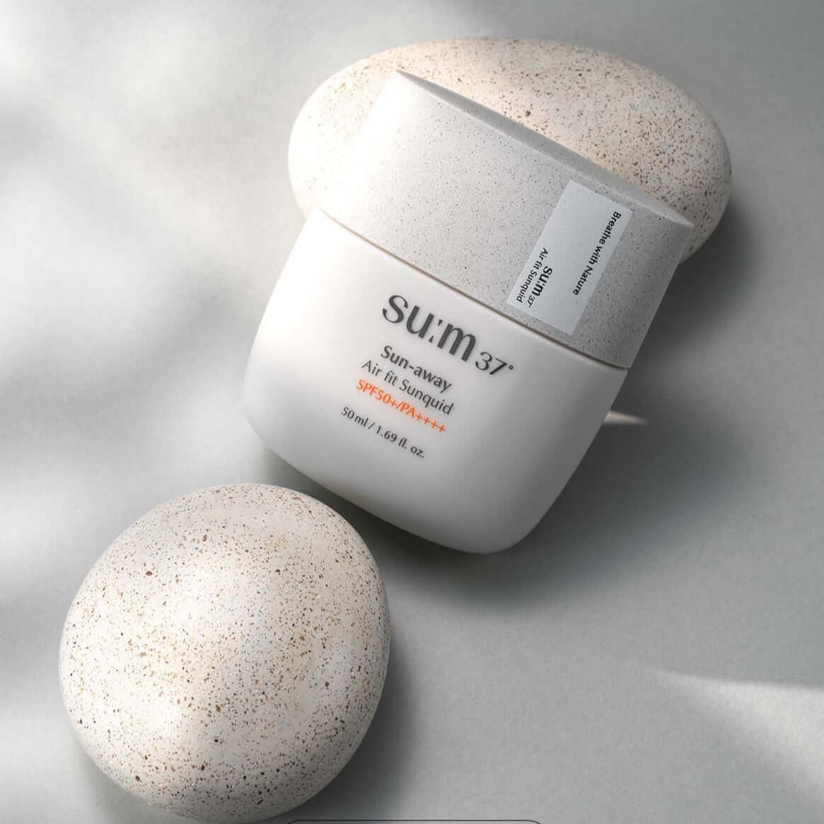 SU:M37 Sun-Away Airfit Sunquid 50+/PA++++ 50ml sun protection product image on a textured background.