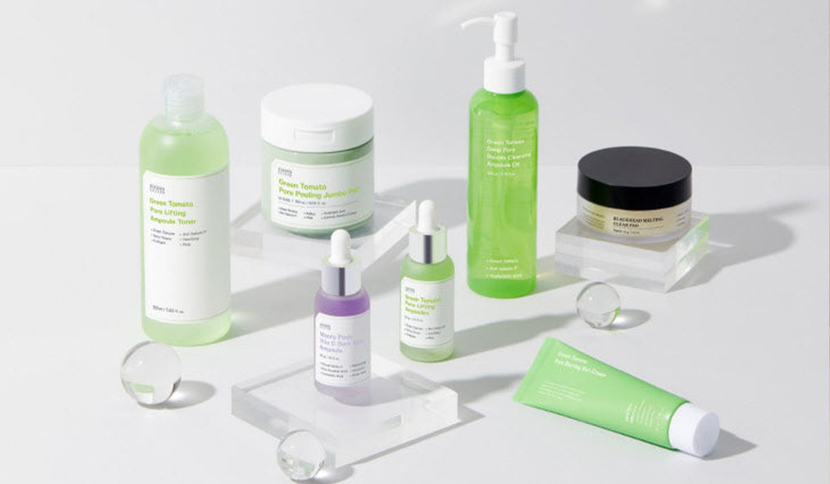 Assorted skincare products including bottles, jars, and tubes arranged on a white background with clear acrylic stands and glass spheres.