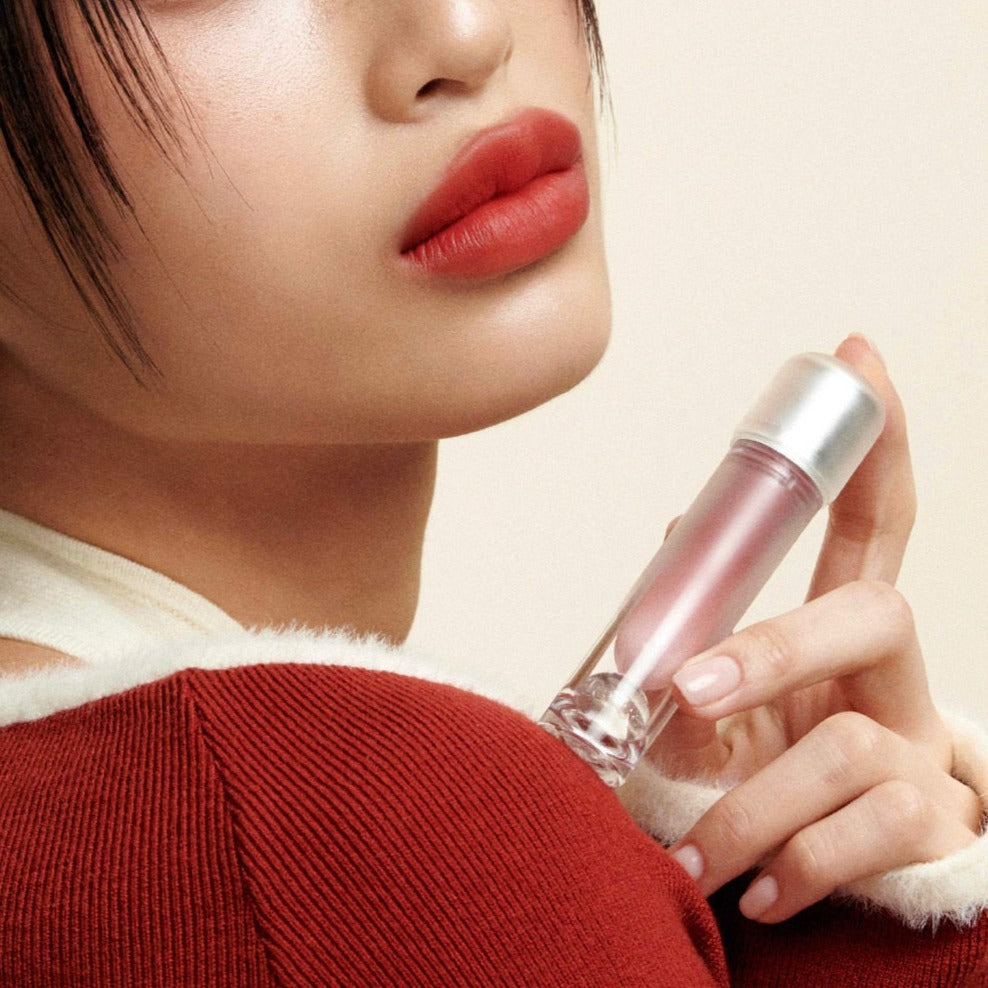 Woman holding TENSE Day Moment Cream Velvet Tint close to her lips, showcasing product texture and design.