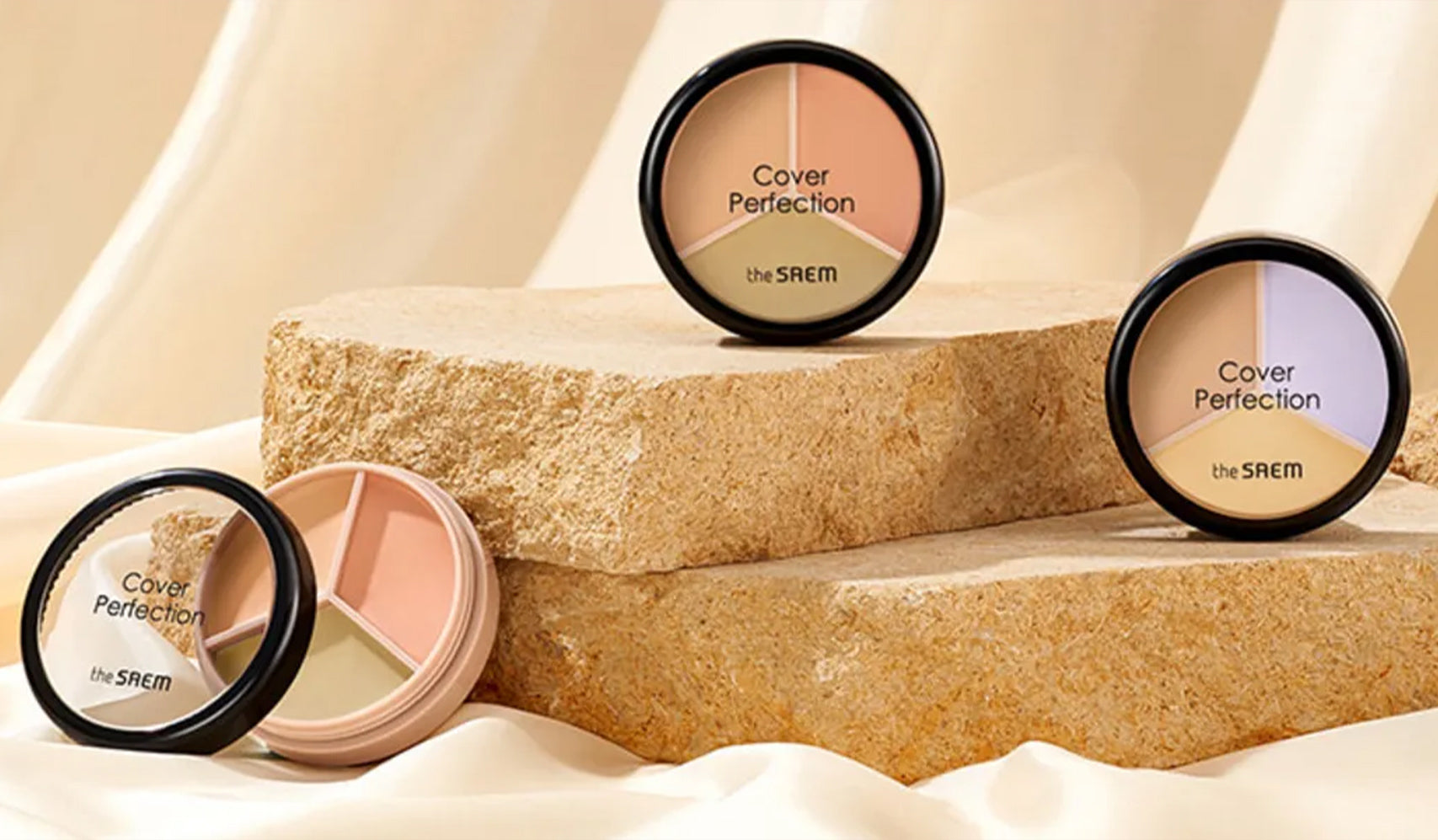 Three Cover Perfection makeup palettes by the SAEM displayed on stone slabs showcasing various shades for flawless coverage.