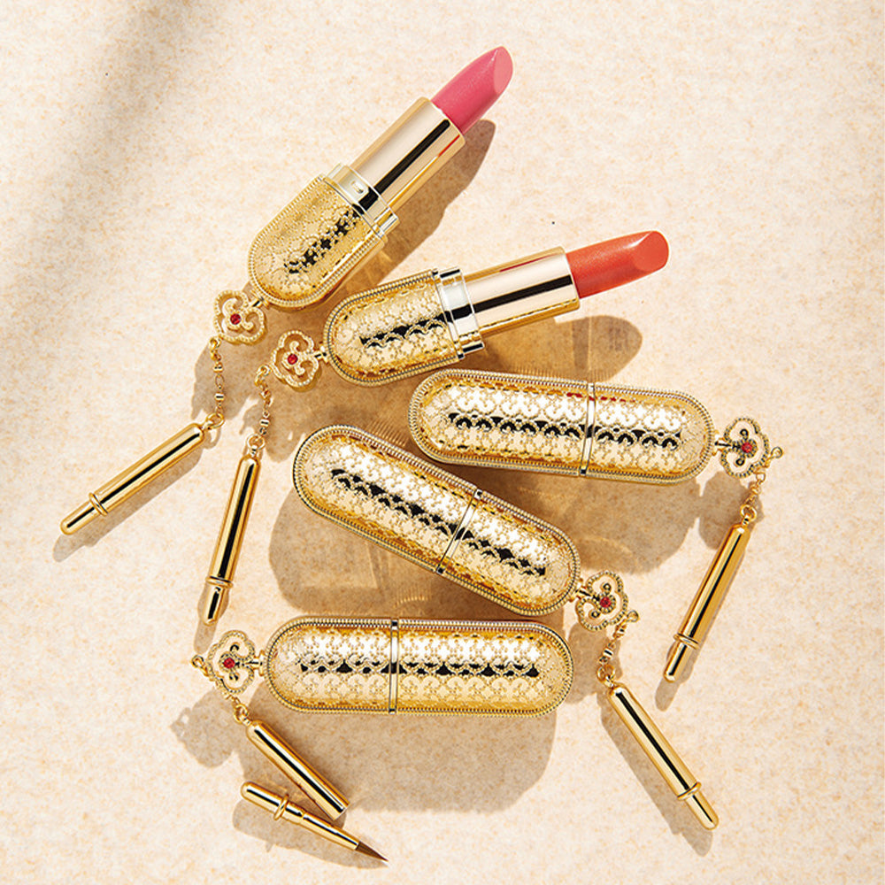 THE WHOO Gong Jin Hyang Mi Luxury Lipstick in royal gold casing with pink and orange shades displayed elegantly on a textured surface