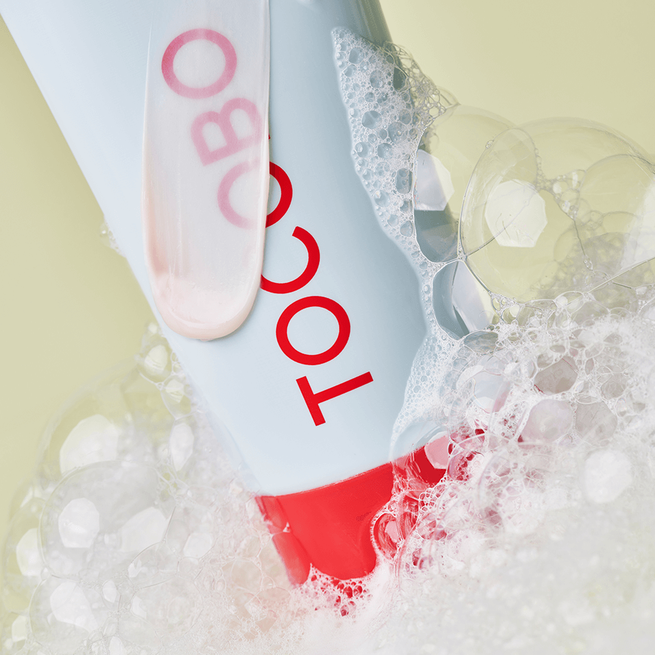 TOCOBO Coconut Clay Cleansing Foam tube surrounded by foamy bubbles, emphasizing its cleansing properties.