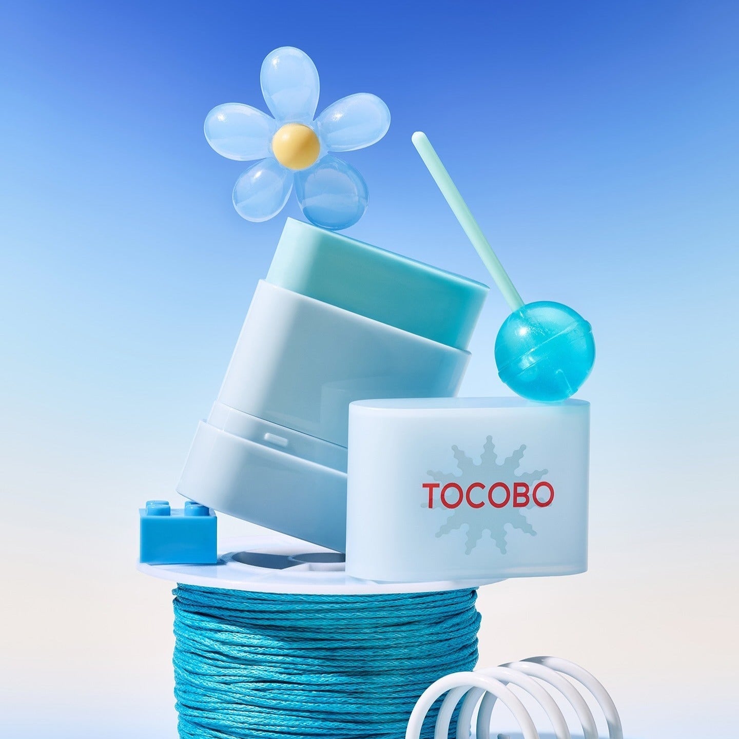 TOCOBO Mini Sun Stick Trio displayed creatively with a floral and blue theme.