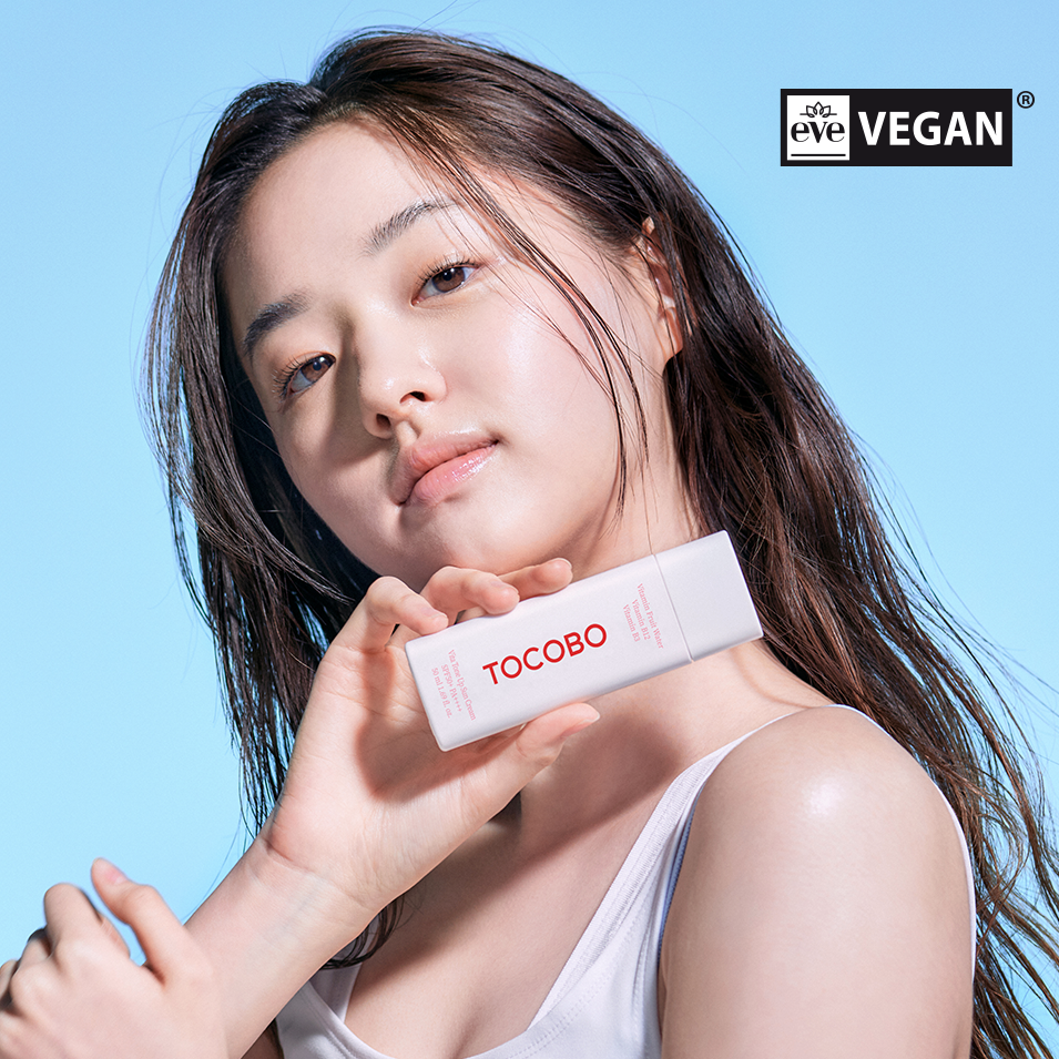 TOCOBO Vita Tone Up Sun Cream 50ml held by a person with a blue background and vegan certification badge.