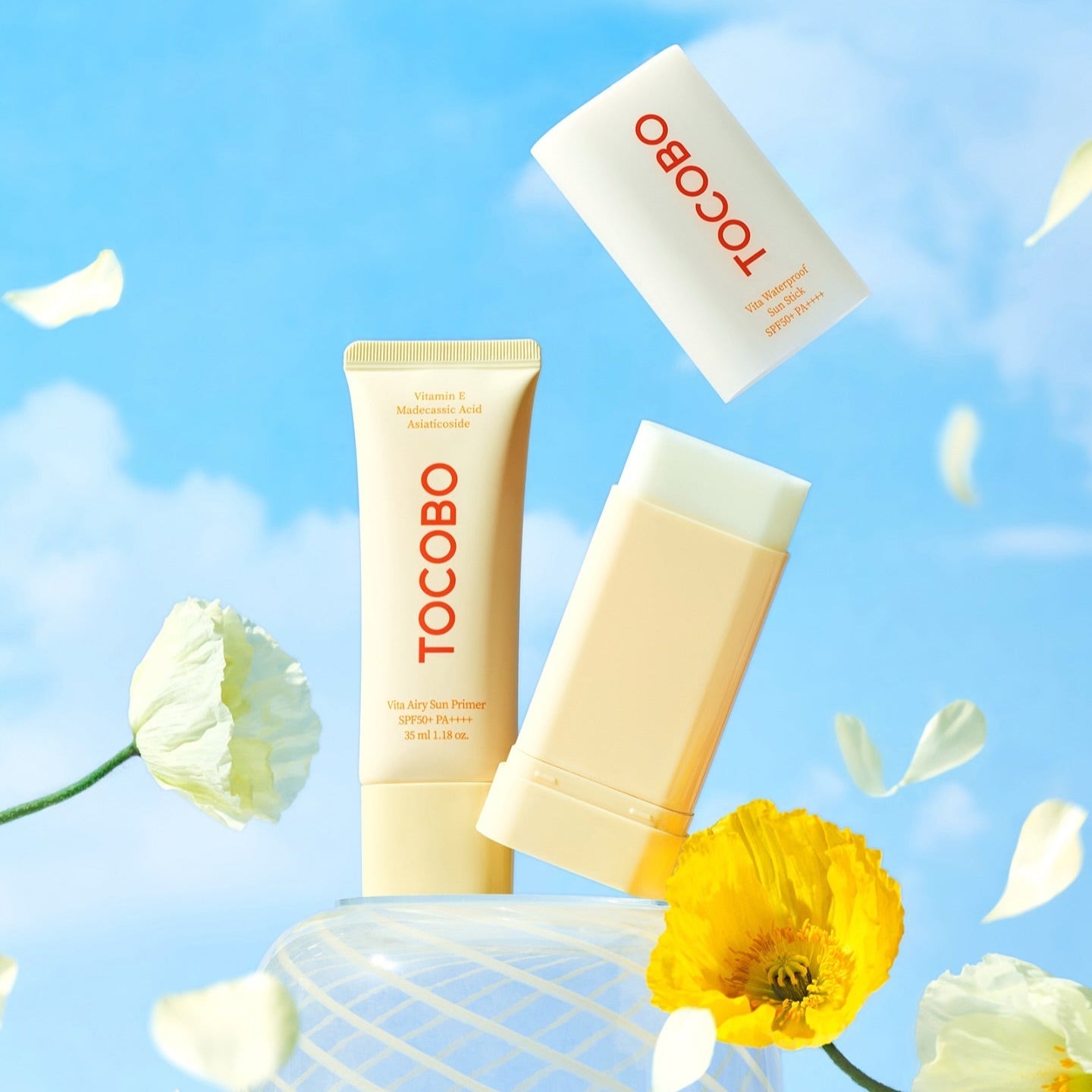 TOCOBO Vita Waterproof Sun Stick displayed with bright flowers against a blue sky background.