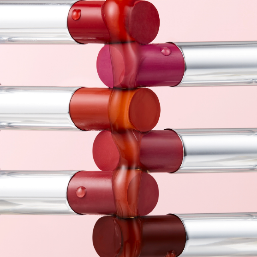 Colorful TONY MOLY Get It Tint Syrup Stick lipsticks arranged creatively against a pink background.