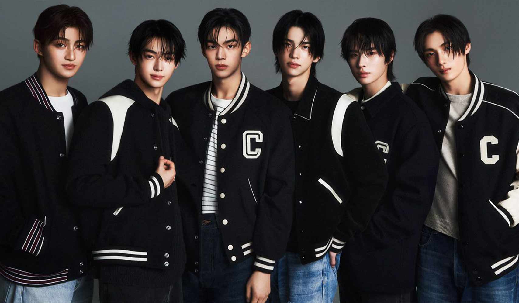 Group of five young men wearing matching black varsity jackets, posing in a studio.