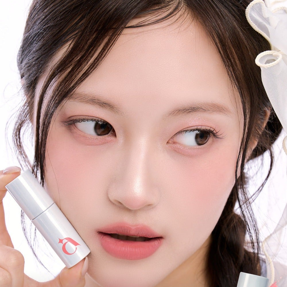 Model holding UNLEASHIA Clound Kiss Velvet Tint, showcasing its smooth application and natural finish lipstick.