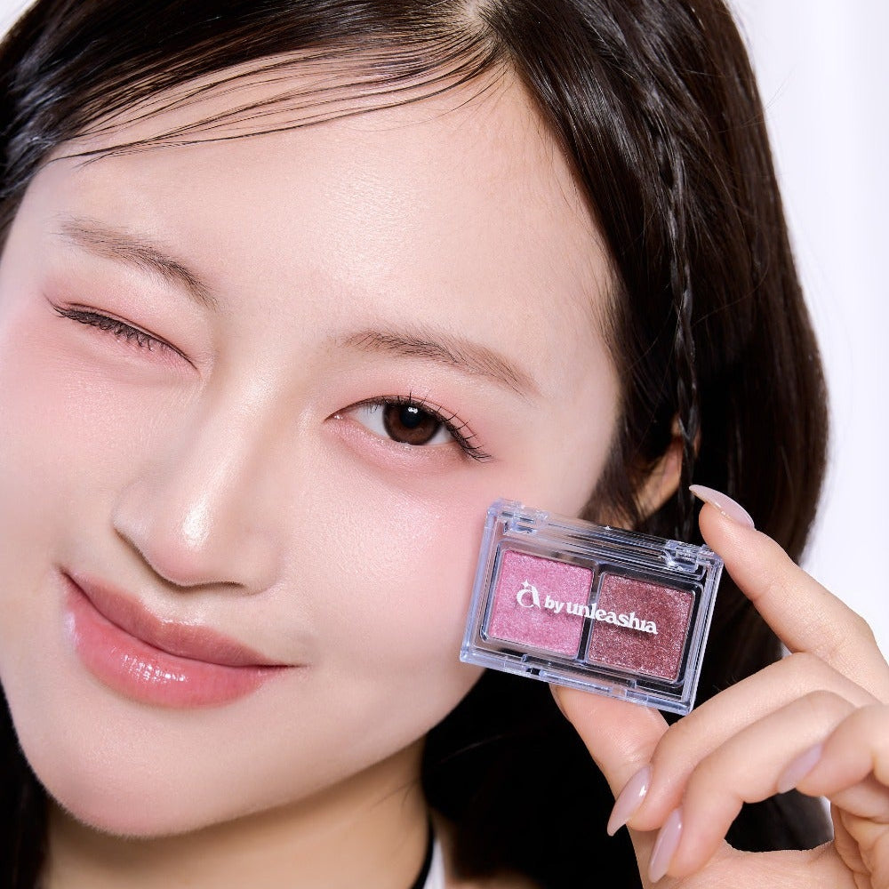 Model showcasing UNLEASHIA Cotton Candy Face Palette with pink hues and sleek design.