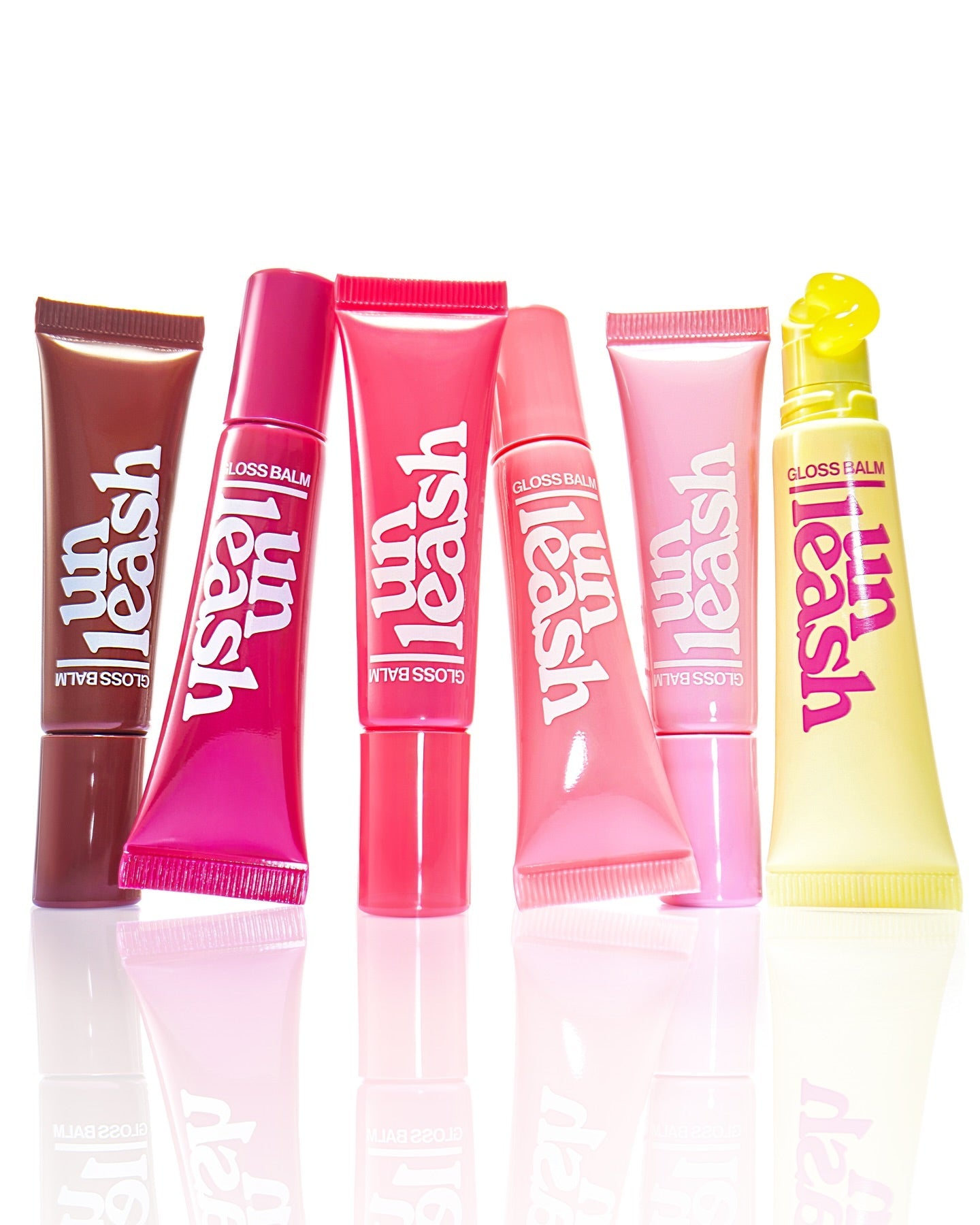 Assorted tubes of UNLEASHIA Sunset Dazzle Gloss Balm in vibrant colors.