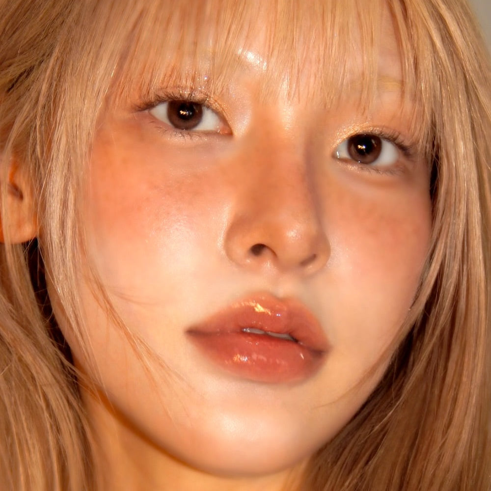 Model wearing UNLEASHIA Sunset Dazzle Gloss Balm with a luminous glow.