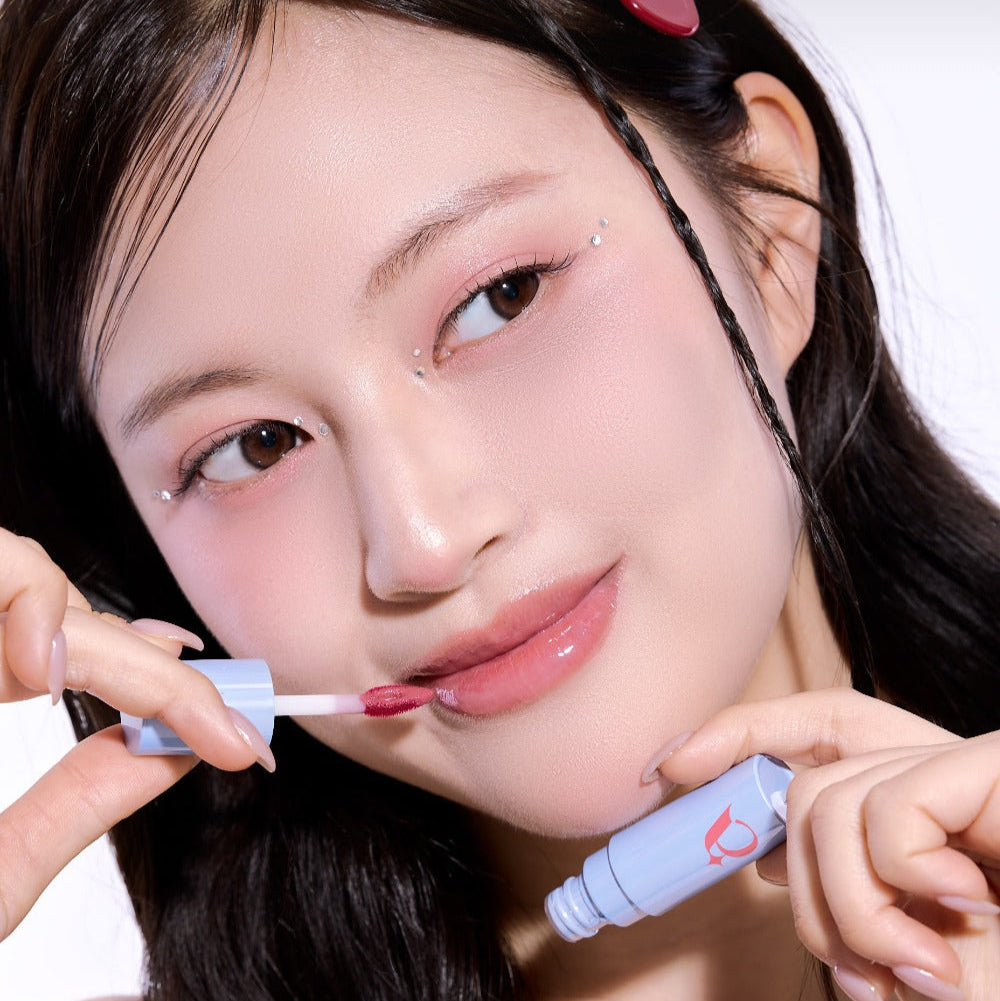 Woman applying UNLEASHIA Tanghulu Glaze Tint on lips for a glossy finish.