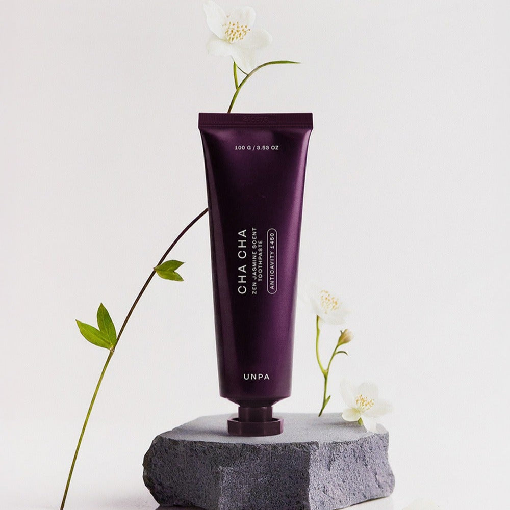 UNPA Cha CHa Zen Jasmine Scent 1450 High Fluoride Toothpaste 100g tube on rock with flowers