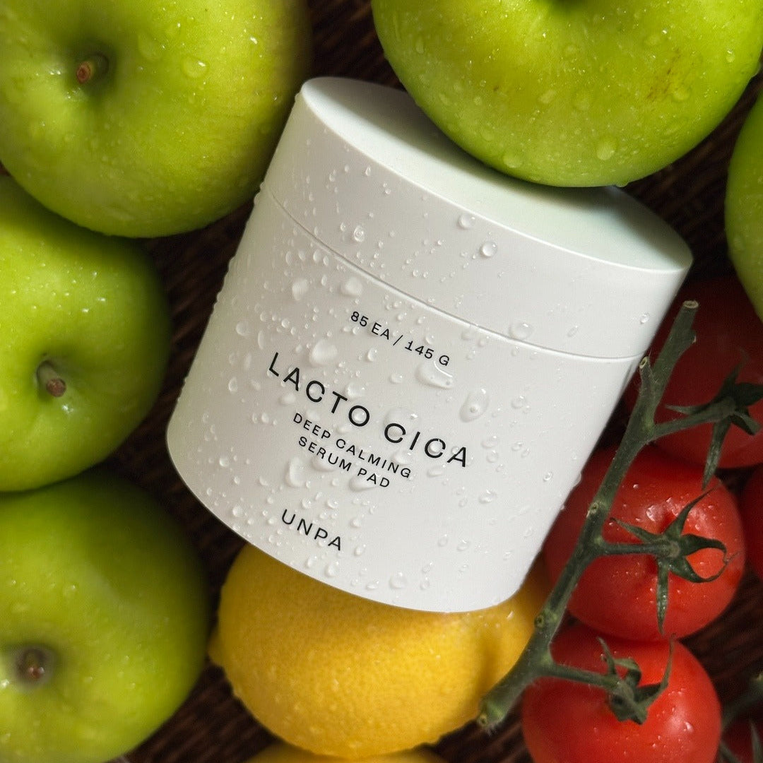 UNPA Lacto Cica Deep Calming Serum Pad 85 Sheets surrounded by fresh fruit for natural elegance.