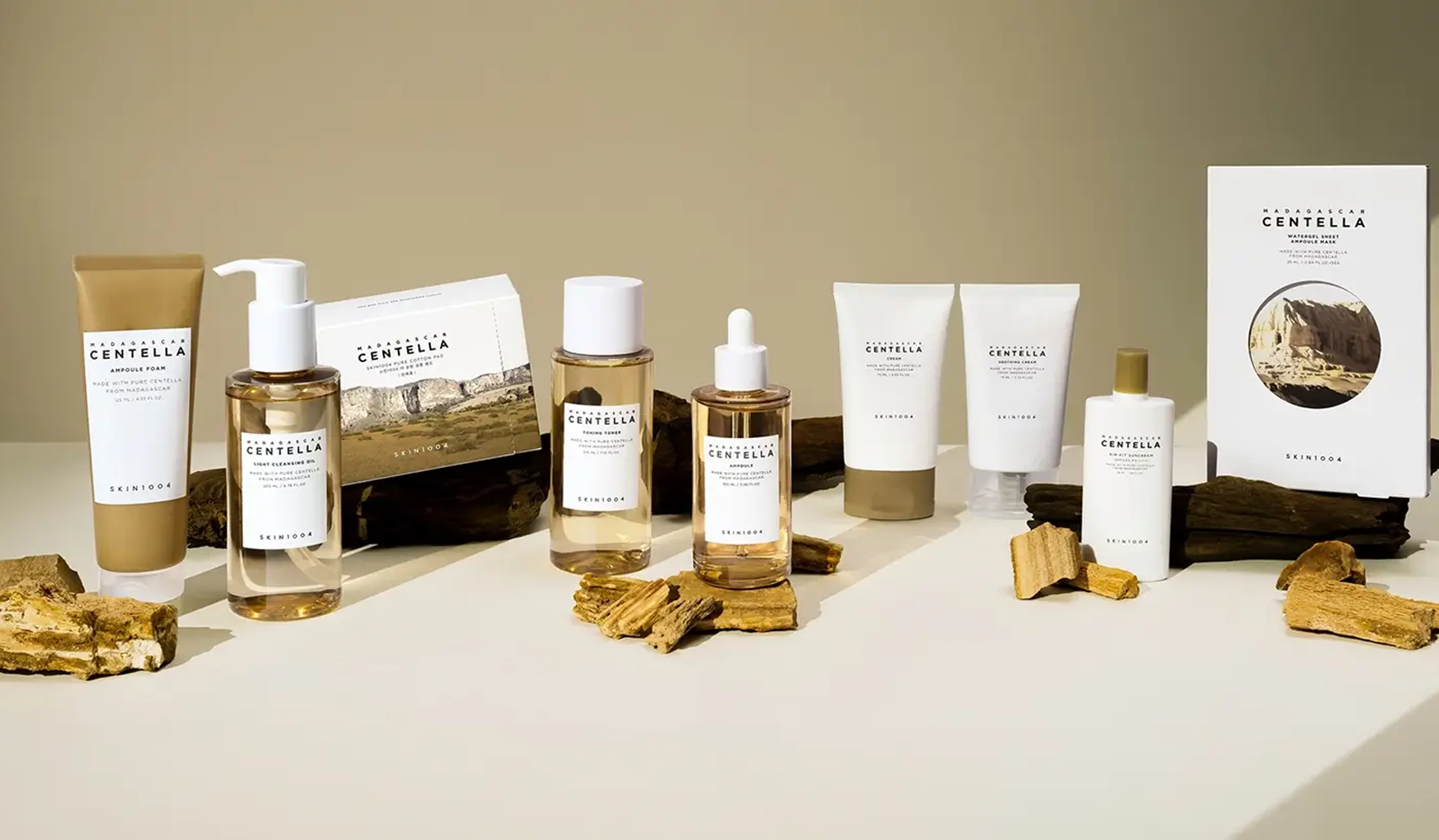 Skincare products with natural ingredients displayed on a table with wooden elements in a minimalist setting.