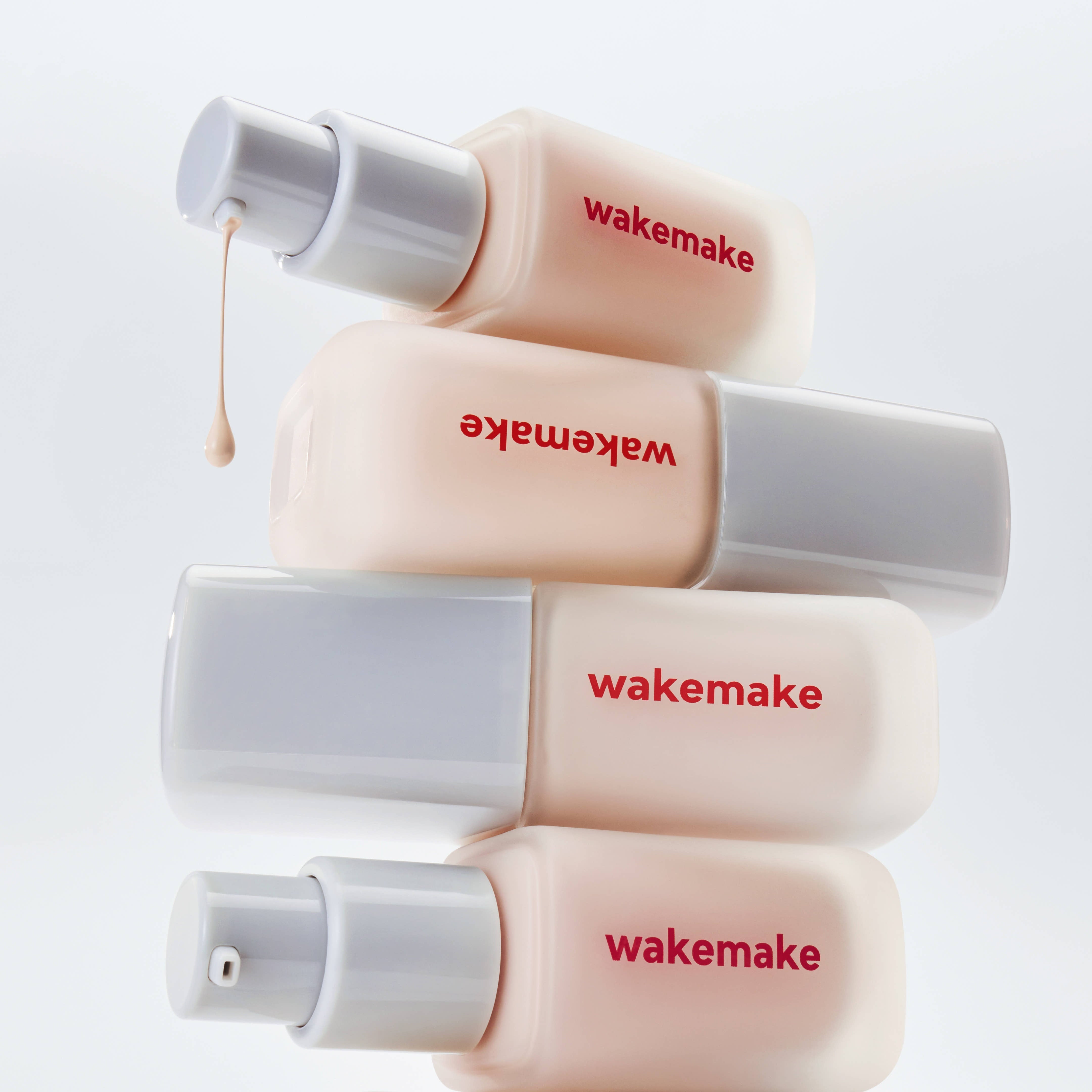 WAKE MAKE Seamless Wear Foundation 30ml bottles displayed creatively with dripping product, highlighting smooth application and finish.