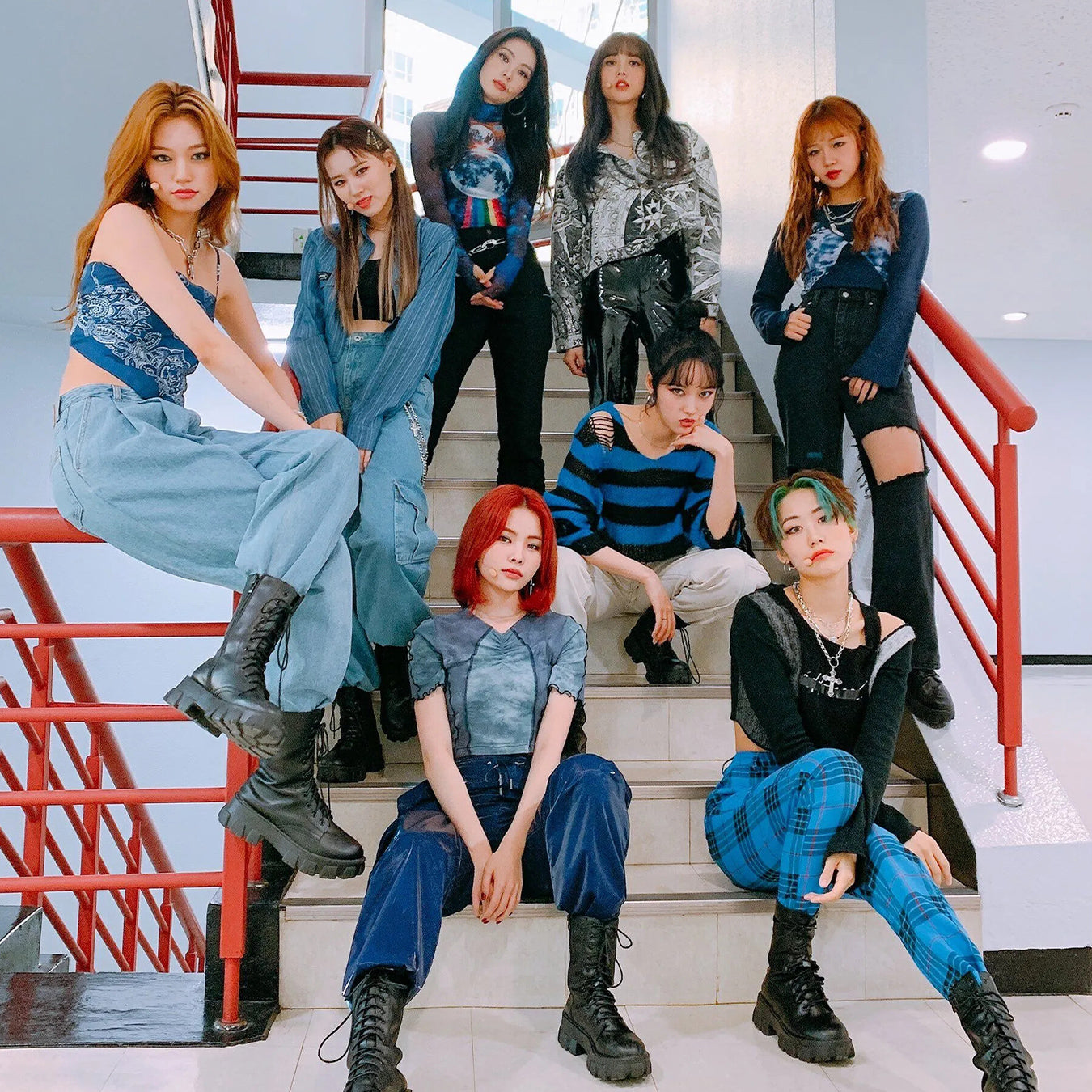 Group of eight stylish individuals posing on a staircase, showcasing trendy fashion with coordinated outfits and confident expressions.