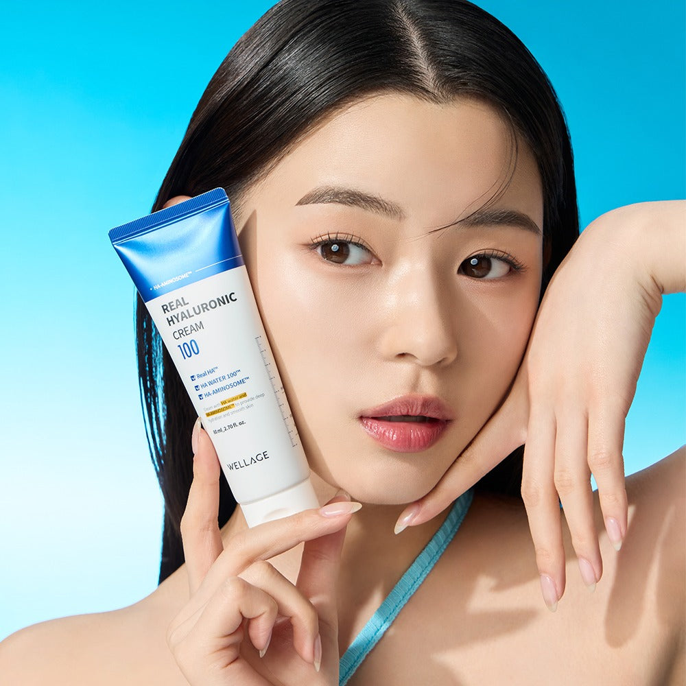 WELLAGE Real Hyaluronic 100 Cream 80ml held by model against blue background, showcasing skincare product.