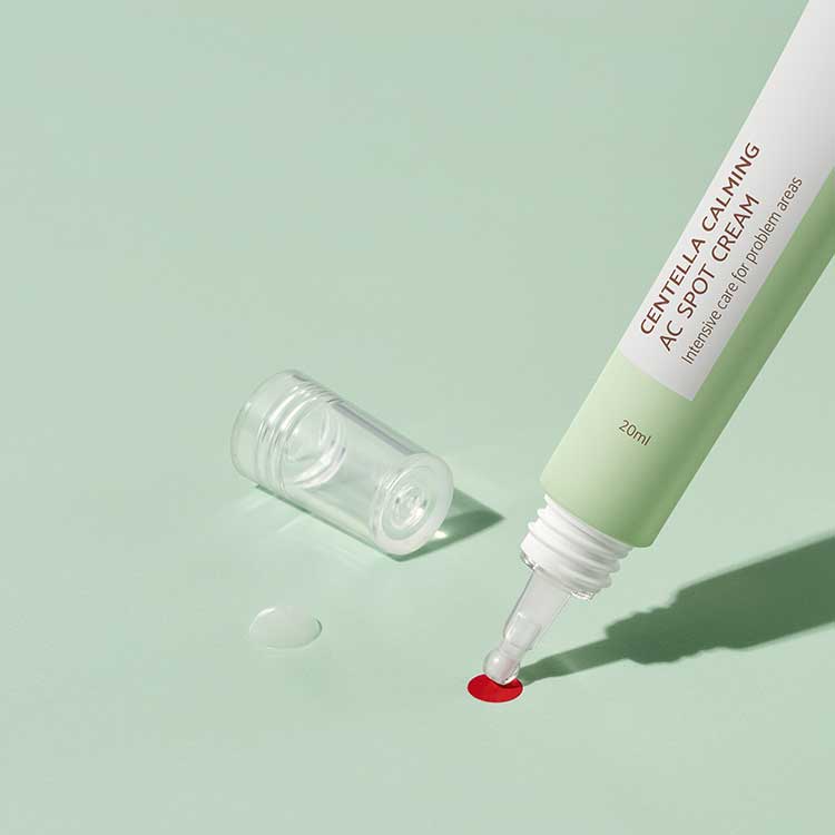 iUNIK Centella Calming AC Spot Cream 20ml tube with lid off, showing application on a green background