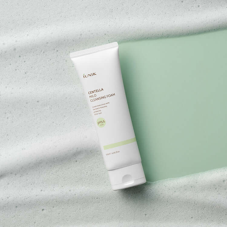 iUNIK Centella Mild Cleansing Foam 120ml tube on a foamy green background, showcasing skincare product packaging.
