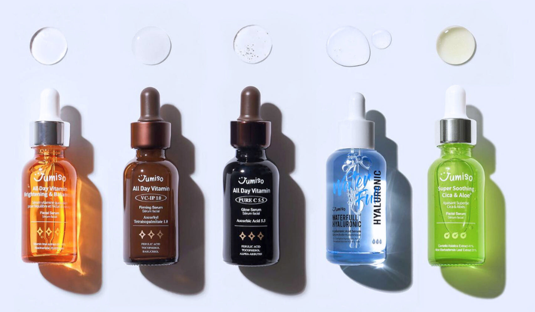 Assorted skincare serums in colorful bottles with droppers on a light background, showcasing beauty and skincare products.