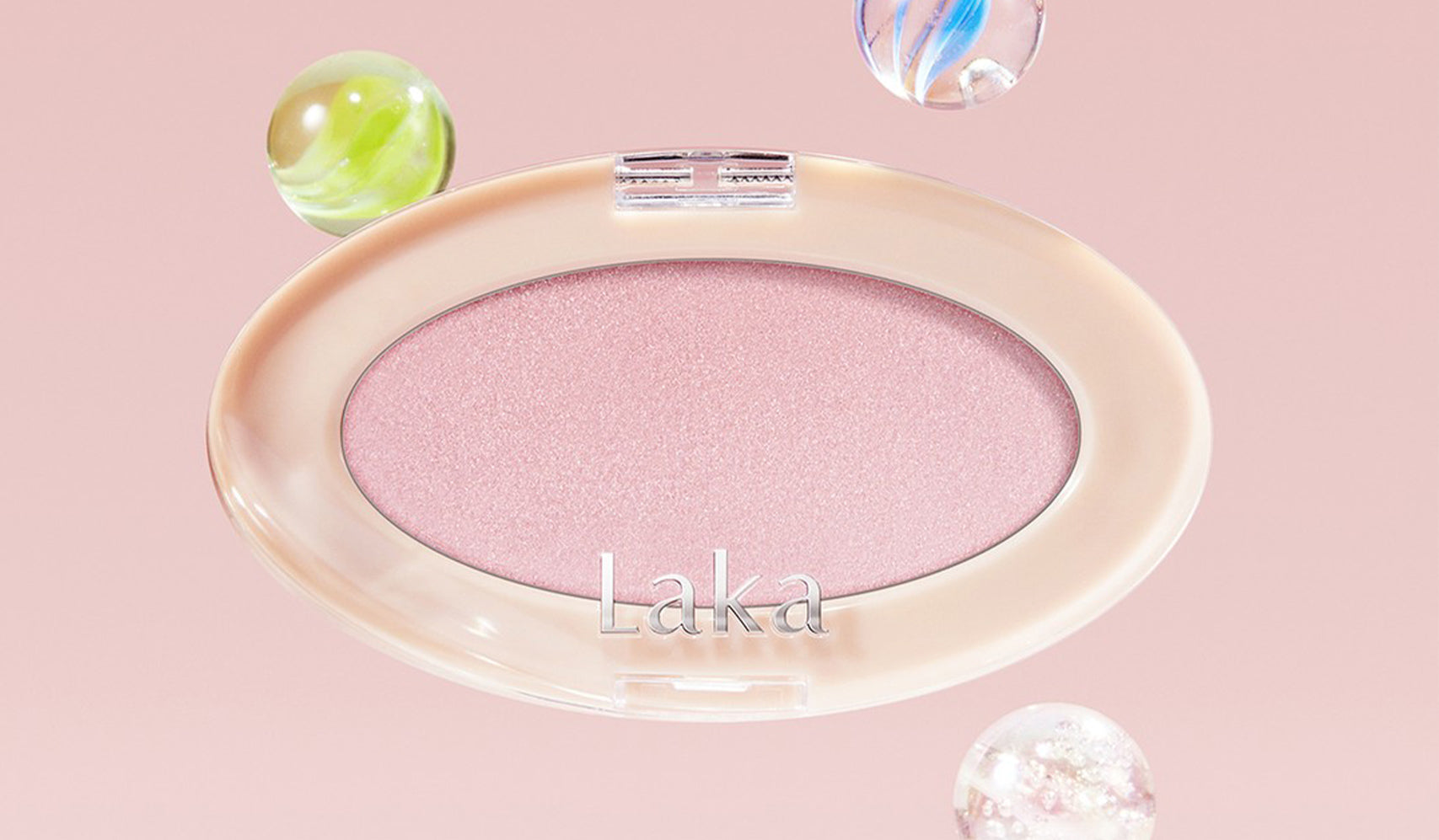 Laka pink eyeshadow palette with decorative glass marbles on a soft pink background