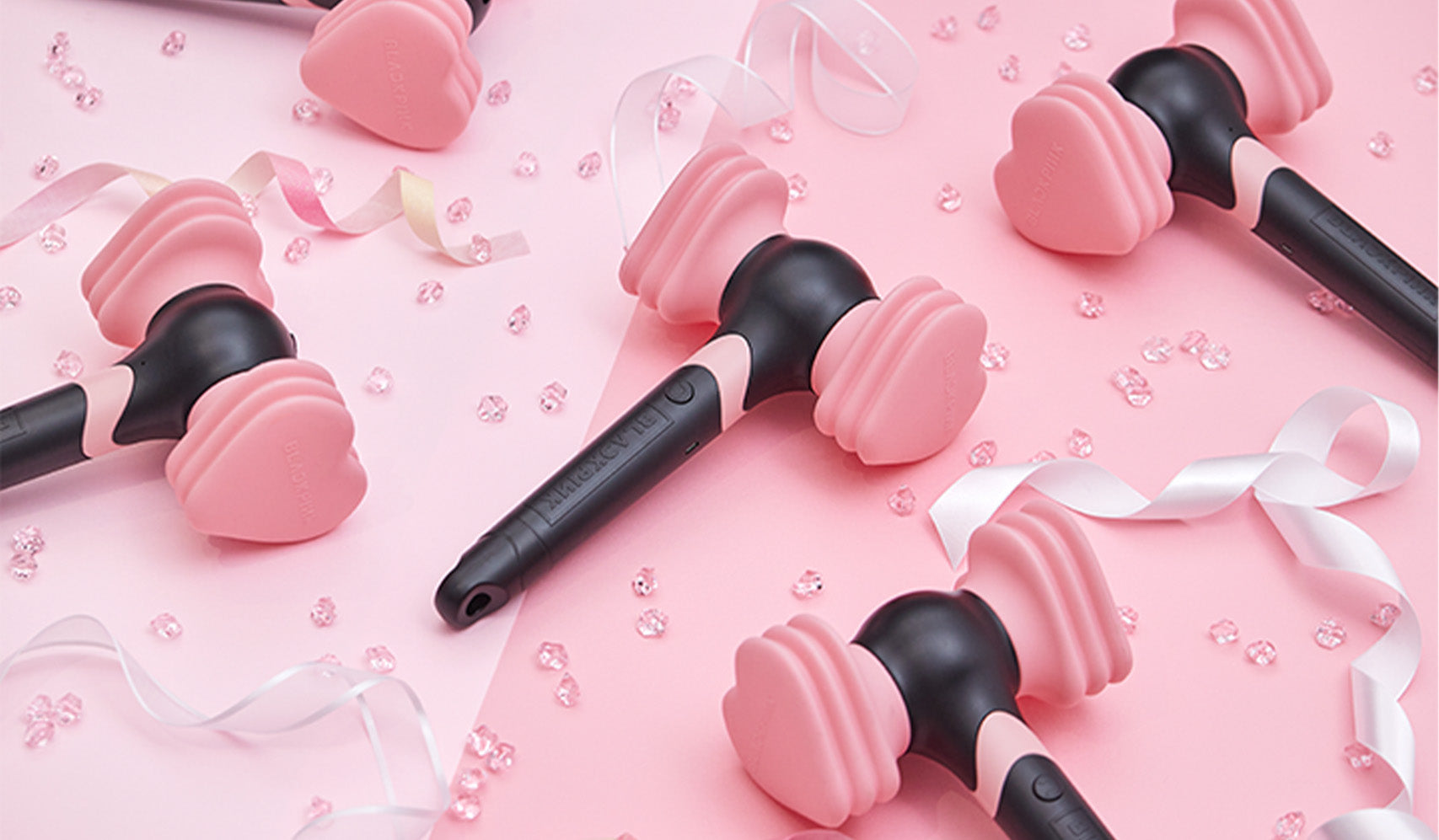Pink and black heart-shaped handheld fans with ribbons and beads on a pink background.
