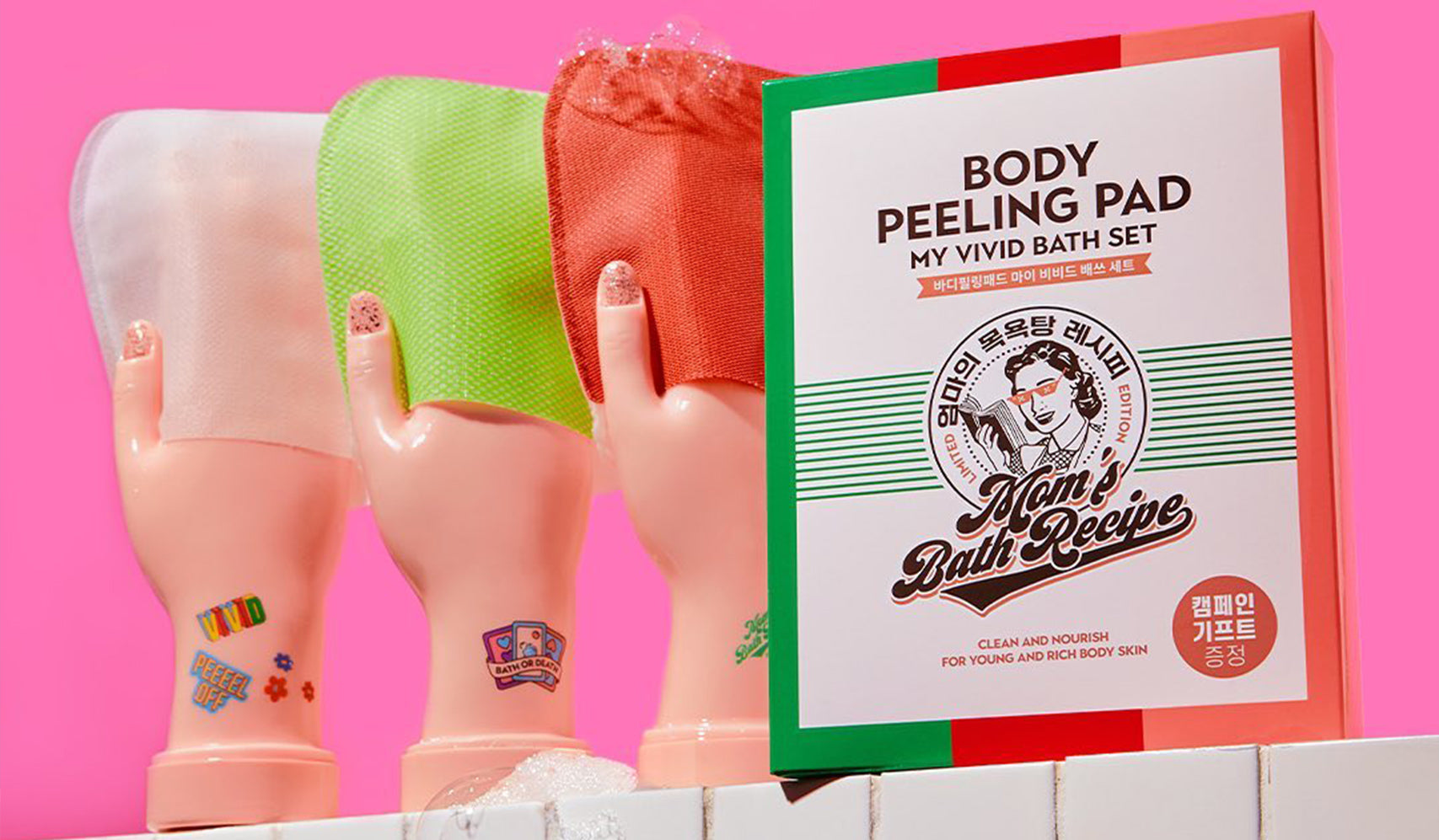 Body peeling pad set with colorful packaging and vivid bath sponges against a vibrant pink background.