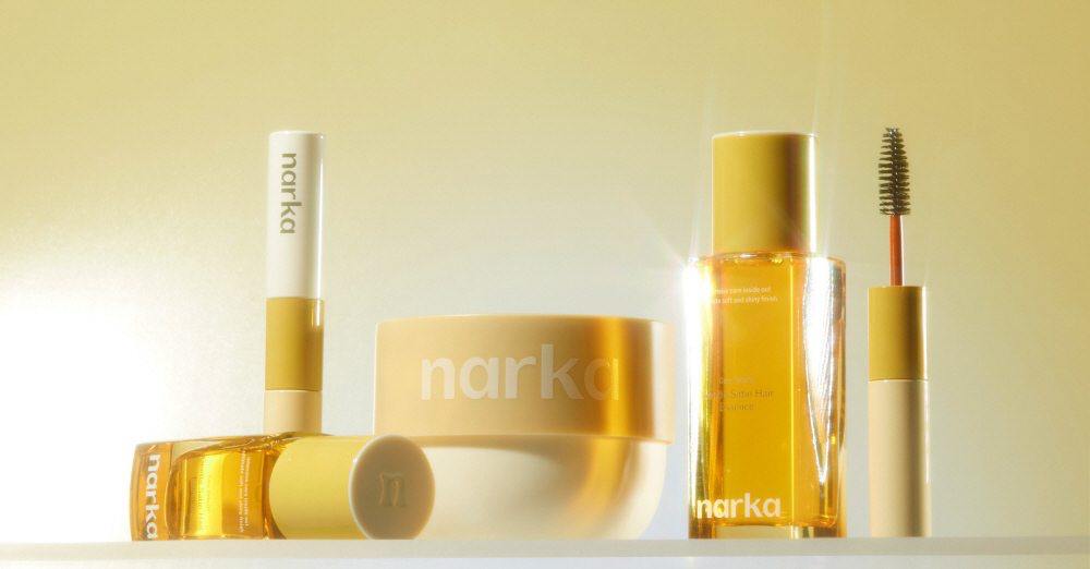 Narka cosmetics product lineup showcasing serum, cream, lipstick, and mascara in elegant gold packaging.